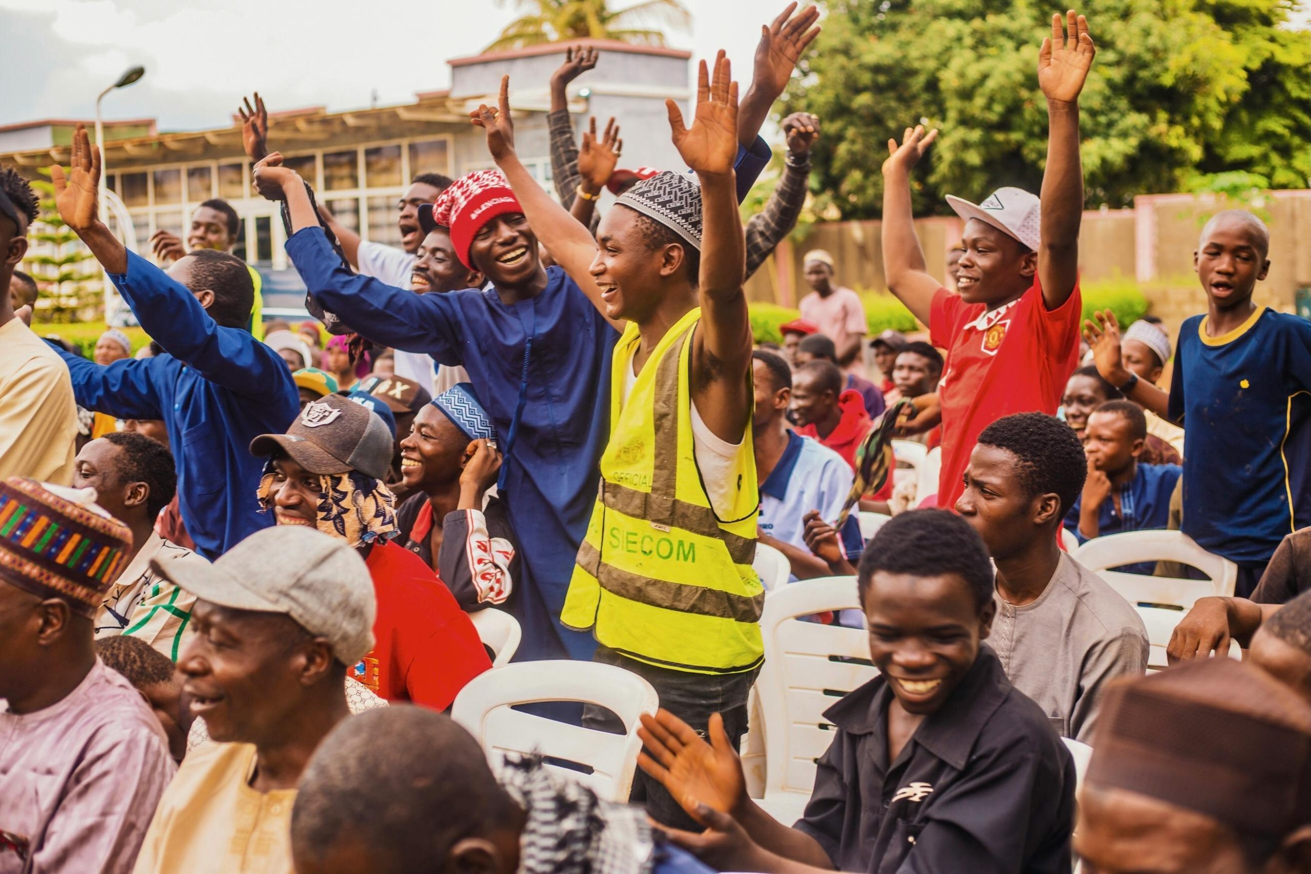 Lively outdoor gathering of diverse individuals in Kaduna, Nigeria, expressing joy and engagement.